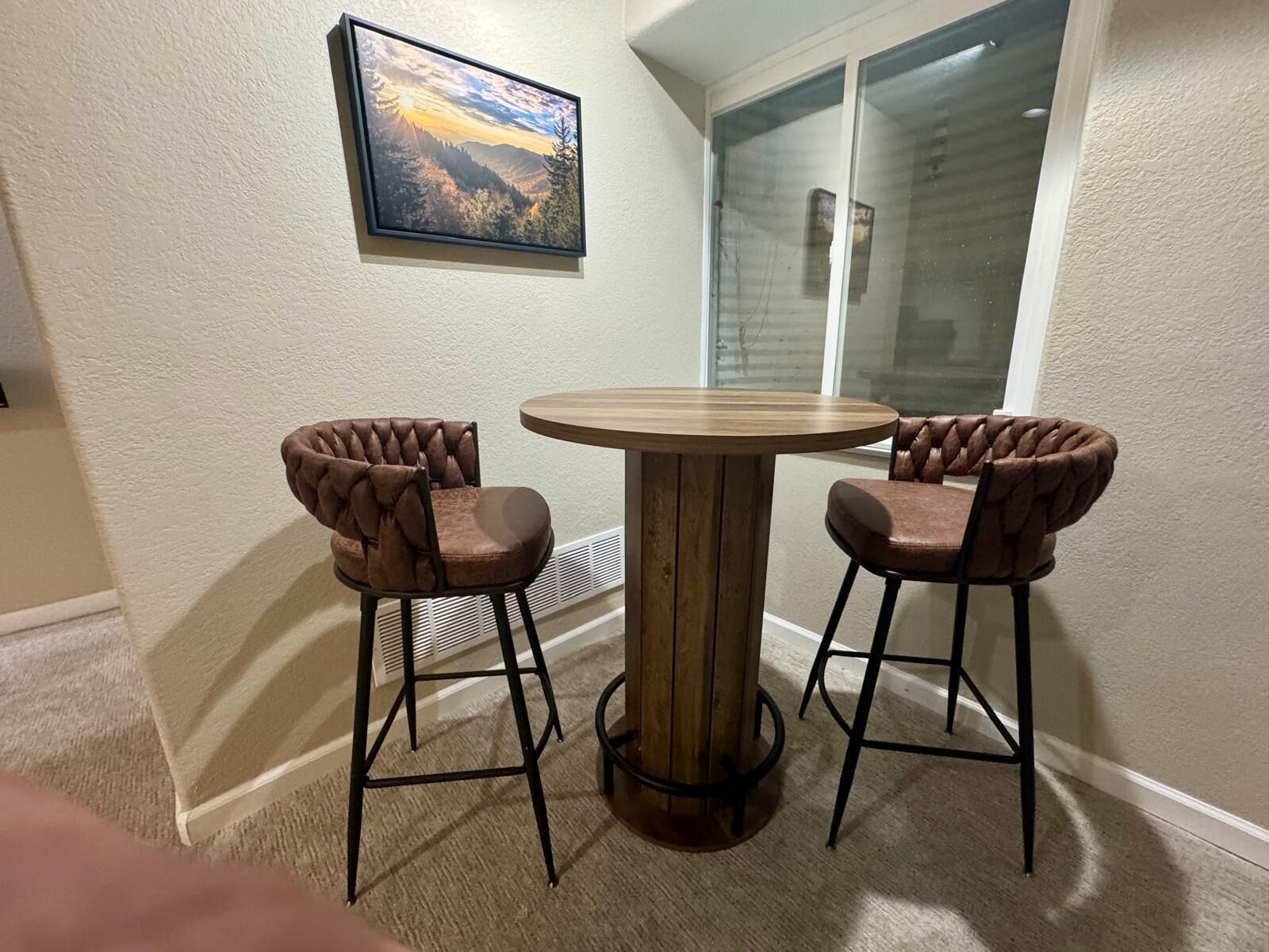 A corner room with a round wooden table and two upholstered chairs.