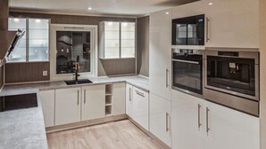 A modern kitchen with built-in appliances, a window, and a wooden floor. - 4 bedroom beautiful home in Limingen (Limingen)