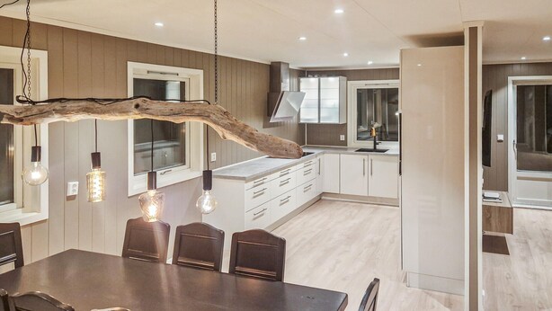 A modern kitchen with white cabinets, a central island, and pendant lighting. - 4 bedroom beautiful home in Limingen (Limingen)