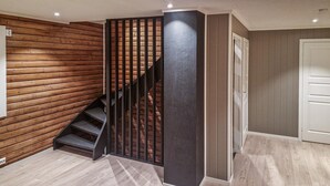 A staircase with wooden paneling on the walls, a black metal railing, and a light-colored wooden floor. - 4 bedroom beautiful home in Limingen (Limingen)