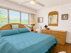 Um quarto com cama, penteadeira, espelho e ventilador de teto.