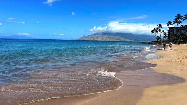 A beach with clear water, a sandy shore, and a mountain in the background. - Relaxing Kihei Getaway - Walk to Beaches, Dining & Shops (Kihei)