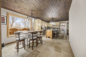 A spacious kitchen with a wooden ceiling, large windows, and a central island.