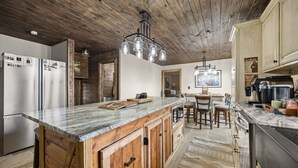 Una cocina con armarios de madera, encimera de mármol y lámpara colgante.