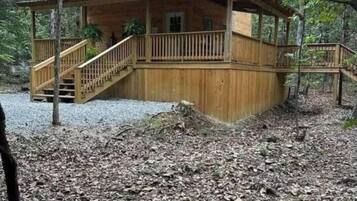 Une cabane en bois dotée d’un porche abrité, d’un escalier et située dans un cadre forestier naturel.
