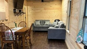 Un intérieur de chalet chaleureux avec un coin repas, un canapé et une fenêtre offrant une belle vue.