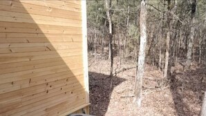 Un bain à remous sur une terrasse en bois, avec vue sur une forêt.