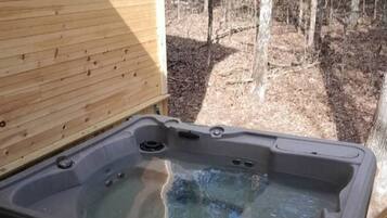 Un bain à remous sur une terrasse en bois, avec vue sur une forêt.