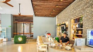 A modern bar area with a wooden ceiling, a stone accent wall, and a bar counter with various items. - Beachfront apartment - Resort style (Santa Marta)