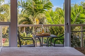 A balcony with a table set for four, surrounded by lush greenery. - Kihei budget friendly 2 bedroom condo across from beach, AC, walk to everything (Kihei)