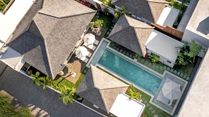 An aerial view of a resort with a swimming pool, multiple lounge areas, and a well-maintained garden. - Villa Saint Laurent by Alfred in Bali (Seminyak)