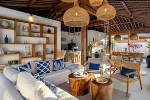 A spacious living area with a high ceiling, wooden beams, and wicker furniture. - Villa Saint Laurent by Alfred in Bali (Seminyak)