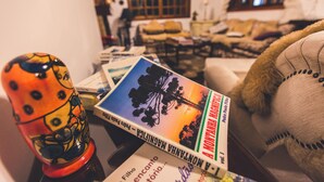 Una habitación con un sofá, un osito de peluche y un libro titulado "A Montanha Mágica".