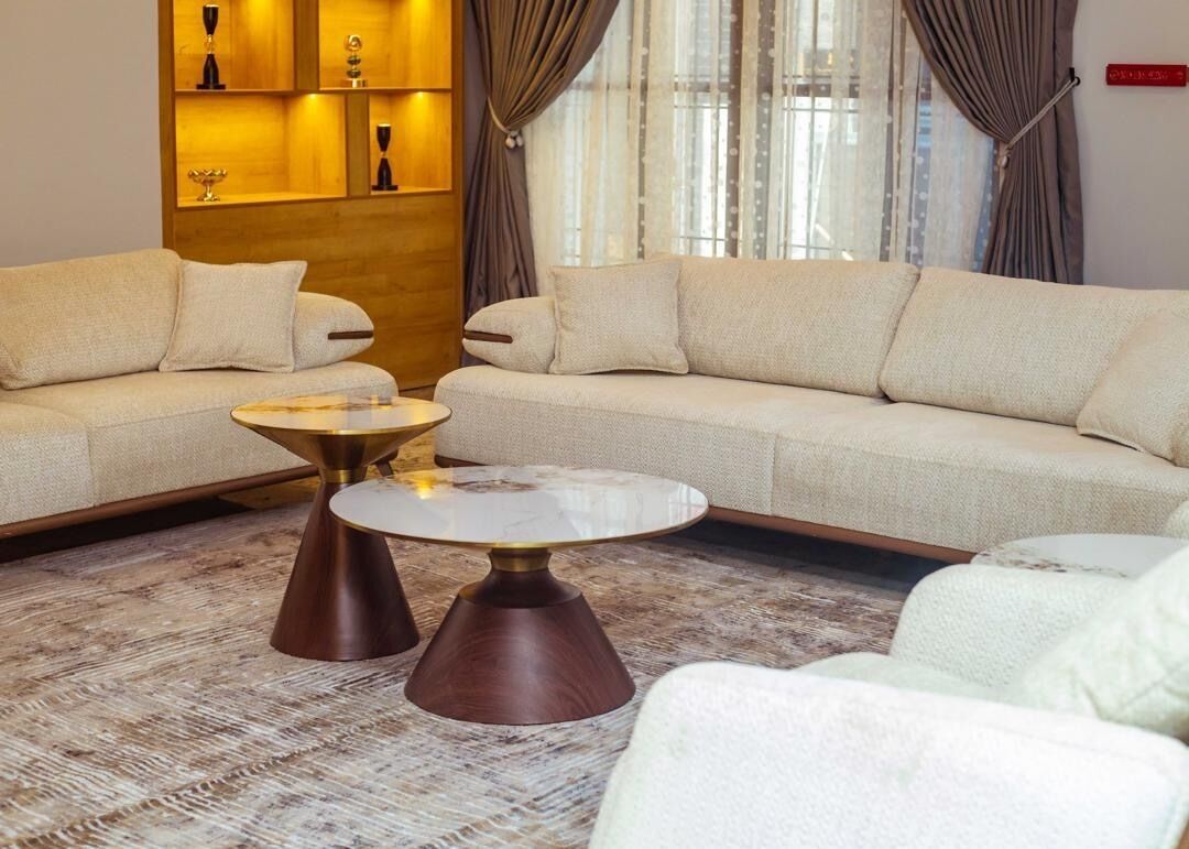 A modern living room with a beige sofa, a round coffee table, and a patterned rug.