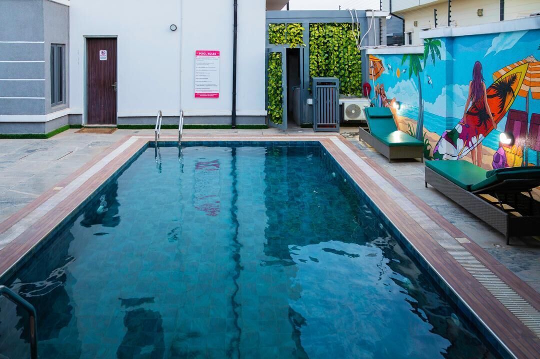 A swimming pool with a wooden deck, a mural, and lounge chairs.