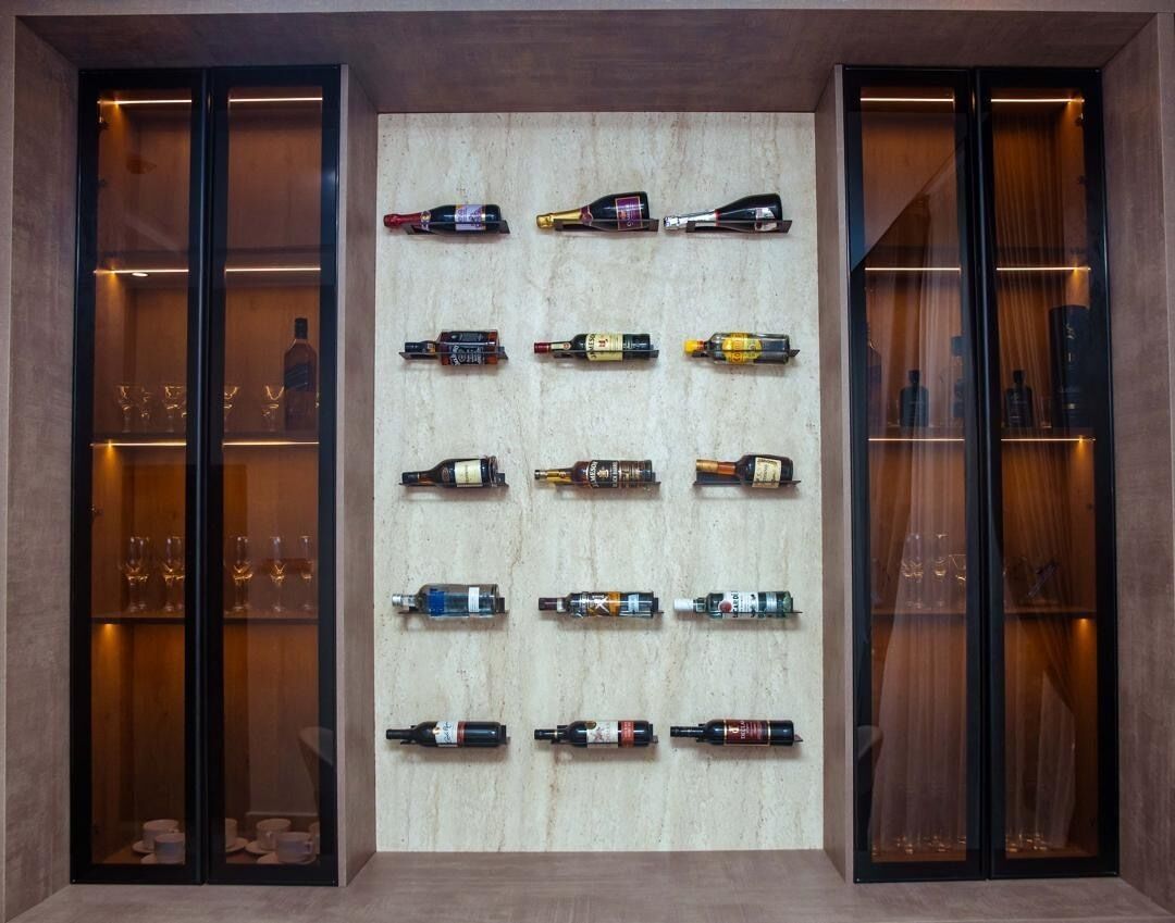 A wall with multiple shelves displaying various bottles, likely for wine or spirits, with glassware on the lower shelves.