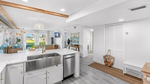 A modern kitchen with a central island, stainless steel appliances, and a view to the outdoors. - Steps to Sand: Ground-Floor Condo with Patio, Private Beach Access & Pool! ☀️ (Satellite Beach)