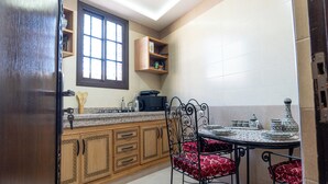 Una cocina con armarios de madera, encimera de granito, una mesa de comedor con sillas y una ventana sobre el fregadero.