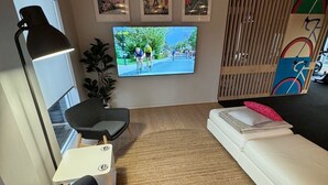 A modern living room with a TV, a sofa, a chair, a lamp, and a decorative wall with pictures. - Entire Private Lodge for Exclusive Use-Perfect for Groups (Normanville)