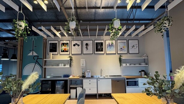 A modern kitchen with wooden countertops, a built-in oven, and a sink. There are hanging plants and framed artwork on the walls. - Entire Private Lodge for Exclusive Use-Perfect for Groups (Normanville)