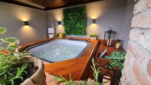 A hot tub with a wooden edge, surrounded by plants and a brick wall. - House by the Dobra River with jacuzzi, panoramic terrace, and space for gatherings. (Zadobarje)