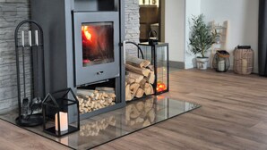 A modern fireplace with a glass door, wood logs, and two lantern-style lights. - House by the Dobra River with jacuzzi, panoramic terrace, and space for gatherings. (Zadobarje)