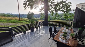 An outdoor patio with a table set for dining, surrounded by potted plants and a view of a green landscape. - House by the Dobra River with jacuzzi, panoramic terrace, and space for gatherings. (Zadobarje)