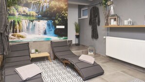 A spa room with a waterfall mural, reclining chairs, a small table with a plant, and a shelf with toiletries. - House in Međimurje for couples with jacuzzi, sauna, terrace, pool, and barbecue (Dragoslavec)