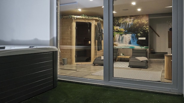 A modern spa room with a hot tub, wooden sauna, and a mural of a waterfall. - House in Međimurje for couples with jacuzzi, sauna, terrace, pool, and barbecue (Dragoslavec)