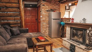 Un salon chaleureux avec un canapé en bois, une cheminée en pierre et un réfrigérateur moderne.