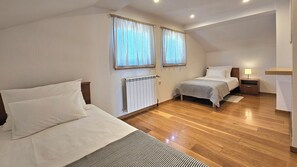 Ein Schlafzimmer mit zwei Betten, einem Heizkörper, einem Nachttisch und einer Lampe.