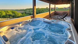 Ein Whirlpool mit Blick auf einen Weinberg und eine Terrasse mit Sitzgelegenheiten.