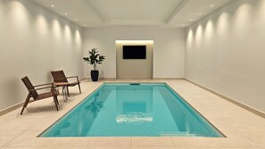 Ein Schwimmbecken mit ebenem Boden, umgeben von Wänden und einer Decke mit eingelassener Beleuchtung.