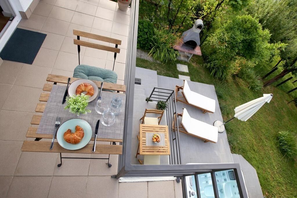 A rooftop terrace with a dining table set for two, outdoor seating, and a hot tub.