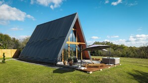 Ein modernes Haus mit geneigtem Dach, großen Fenstern und einer Terrassenanlage mit Gartenmöbeln.