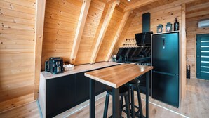 Eine kleine Küche mit Holzvertäfelung, einem schwarzen Kühlschrank und einer Kaffeemaschine.