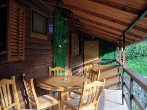 A wooden cabin with a round wooden table and four chairs, a wooden door with a toilet sign, and a window with blinds. - Spacious lakeside home for 15 guests, celebrations and active stays. (Orahovica)