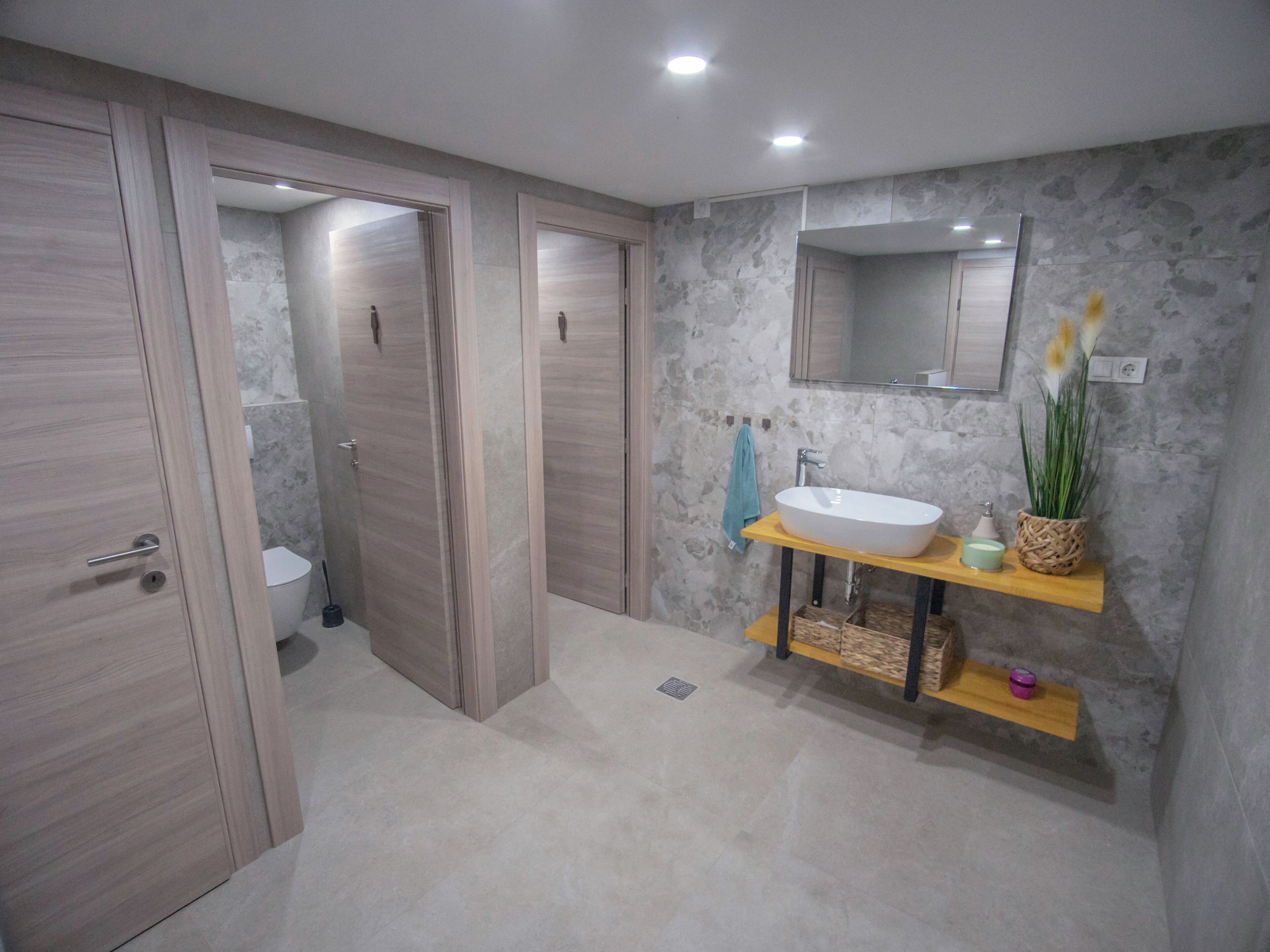 Un bany modern amb un mirall gran, un lavabo i un vàter.