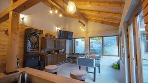 Une cuisine chaleureuse avec des poutres en bois, une table de baby-foot et un jeu de fléchettes.