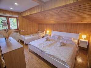 A wooden-paneled room with two single beds and a larger bed, equipped with bedside lamps and towels. - Spacious lakeside home for 15 guests, celebrations and active stays. (Orahovica)
