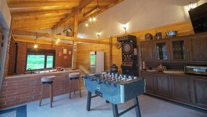 Un espace intérieur accueillant avec une table de baby-foot, un jeu de fléchettes et un coin bar équipé de tabourets.