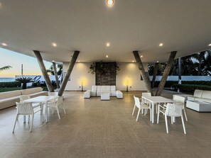 Un espace extérieur aménagé avec des meubles blancs, un sol en pierre et une vue sur l’océan.