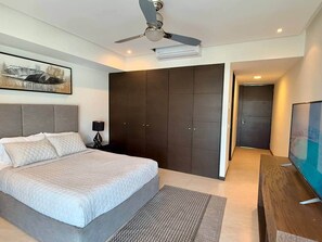 Une chambre à coucher moderne, équipée d’un lit, d’un ventilateur de plafond, d’une télévision et d’une armoire.