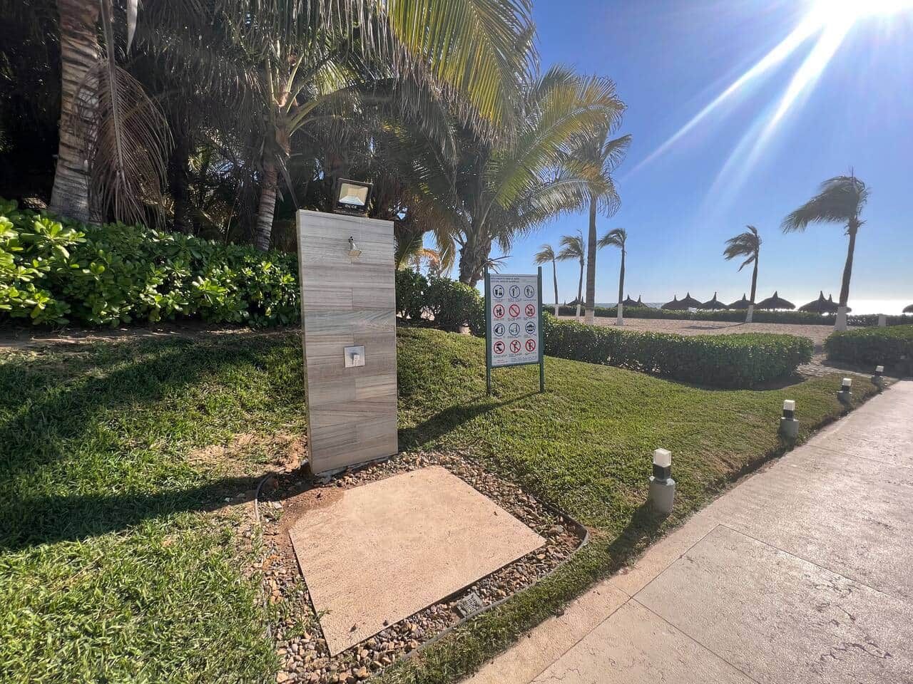 Un sendero que conduce a un edificio con un cartel, rodeado de follaje y palmeras.