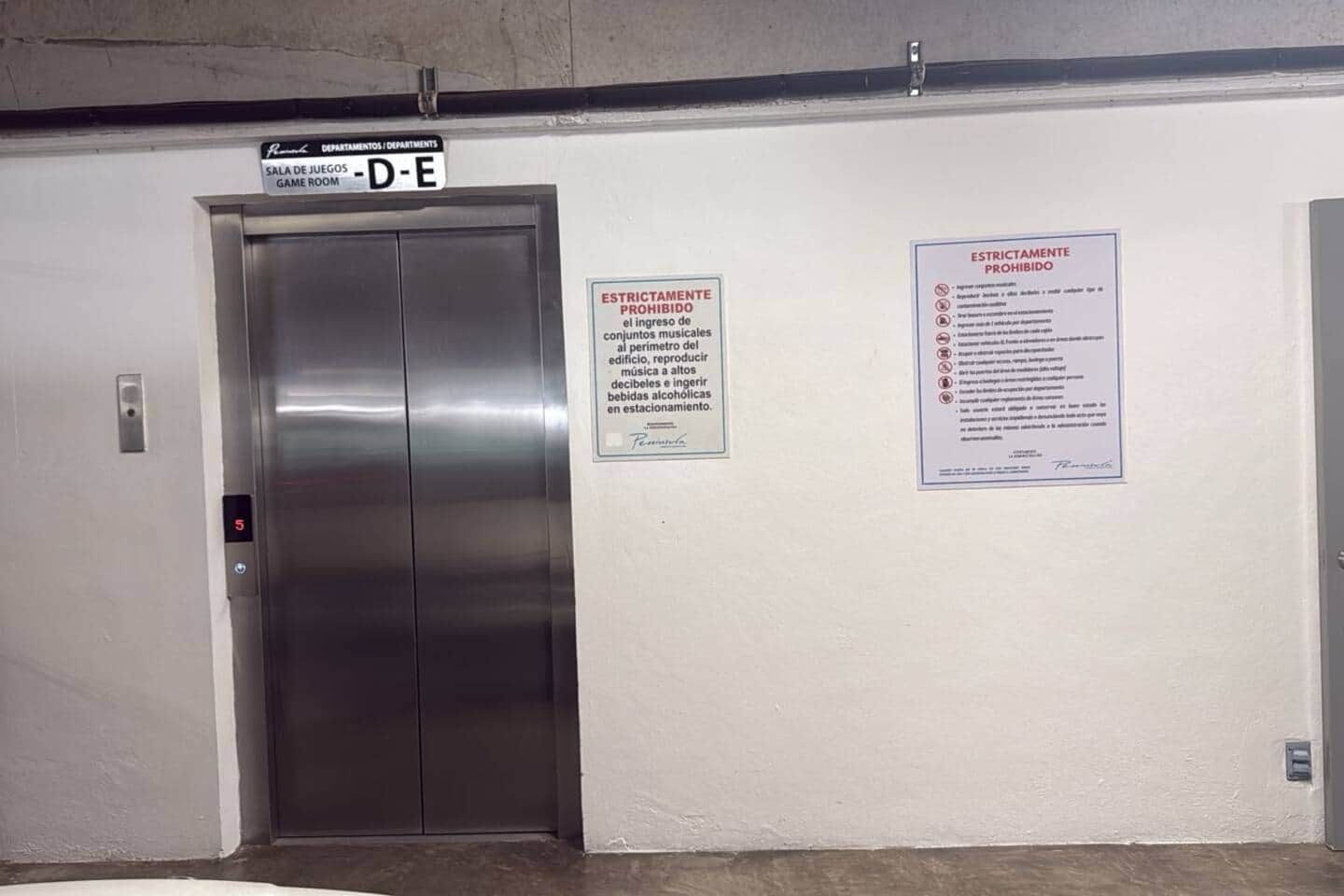 An elevator with a sign indicating 'Game Room' and two notices on the wall.