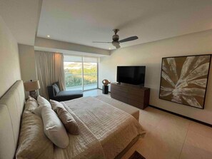 Ein modernes Schlafzimmer mit einem großen Bett, einem Fernseher, einem Deckenventilator und einem großen Fenster.