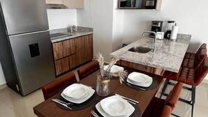 Een moderne keuken met houten kastjes, een roestvrijstalen koelkast en een granieten aanrecht.