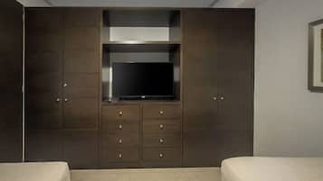 Ein Schlafzimmer mit großem Kleiderschrank, Flachbildfernseher und zwei Betten.