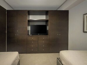 A bedroom with a large wardrobe, a flat-screen TV, and two beds. - Peninsula Mazatlan Floor 27: Exclusive 3-Bedroom Oceanfront (Mazatlan)