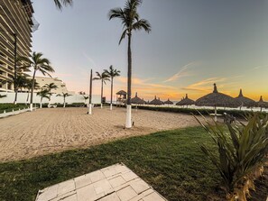 A beach with palm trees, a pathway, and a building in the background.